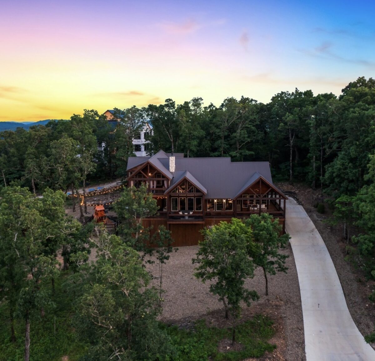 Carter Mountain Lodge — an aerial view of a brown log cabin with a long drive and playset at sunset