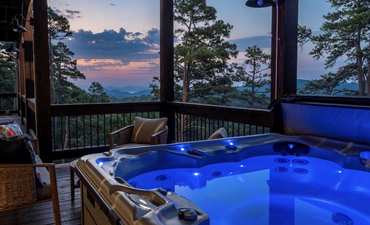 Cliffhanger — a lit hot tub on a covered cabin deck overlooking the hills at dusk