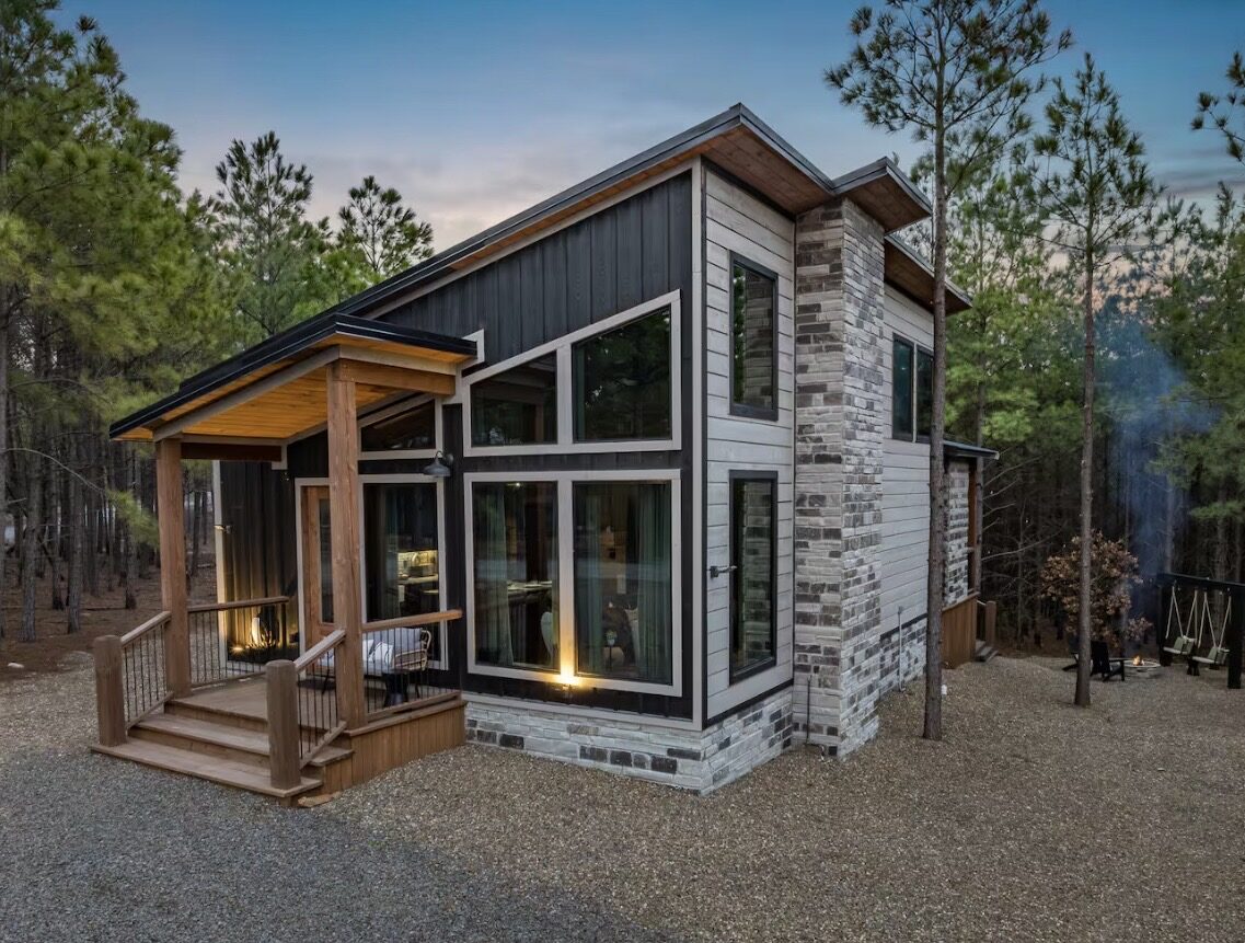 Relaxicab — a small modern cabin with a stone chimney and covered porch in the pines