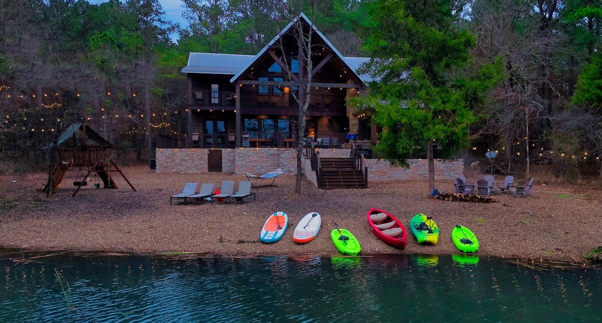 Skippin Rocks — a cabin on a pond at dusk with kayaks and paddleboards along the shore