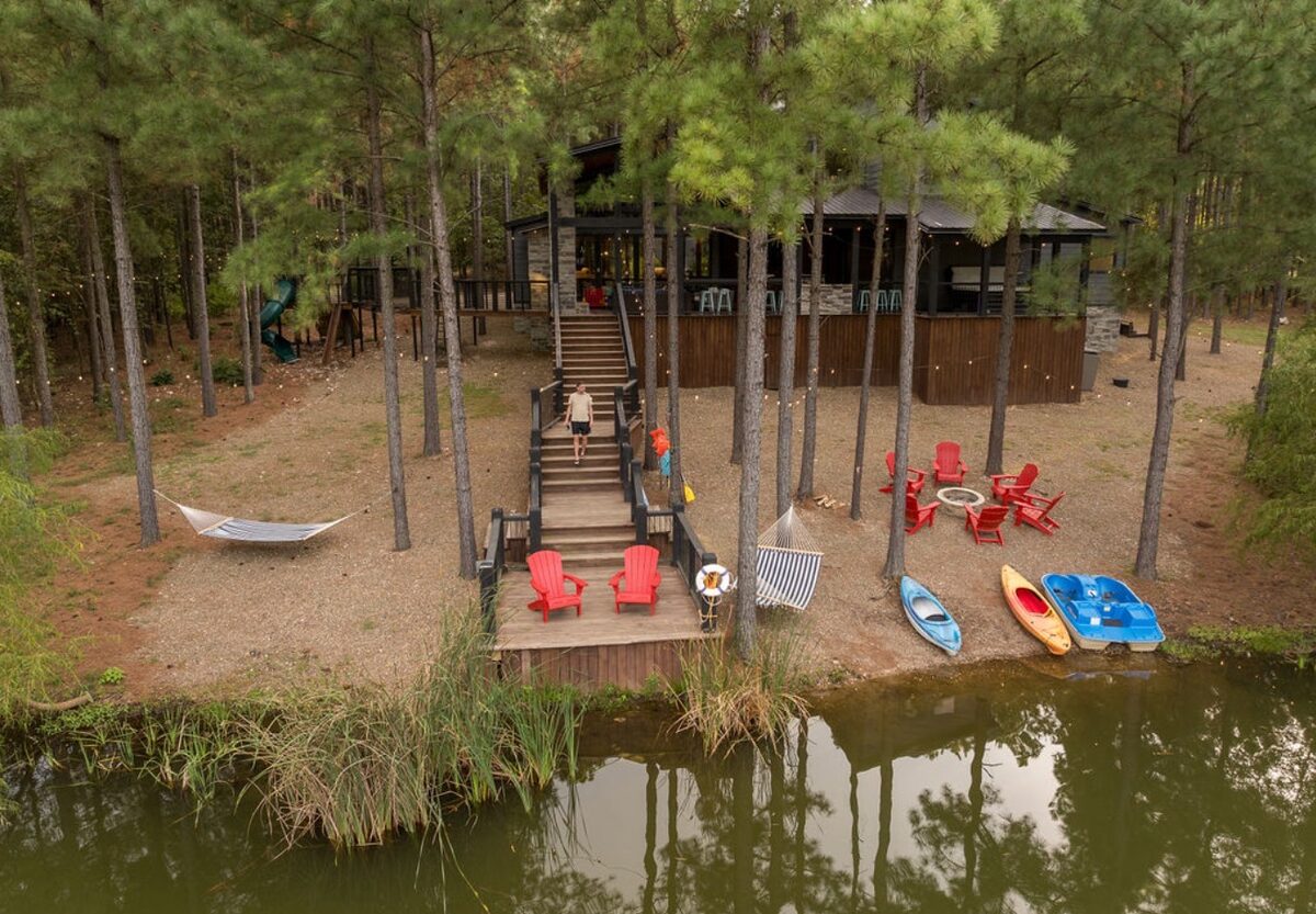 The Cove — an aerial view of a cabin on a private pond with kayaks, a hammock and a fire pit