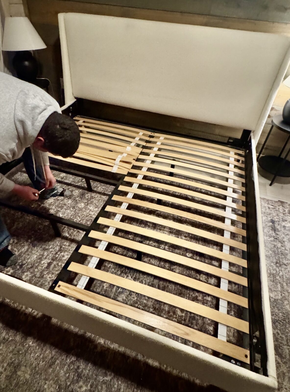Hochatown Premier crew member assembling an upholstered bed frame in a cabin bedroom