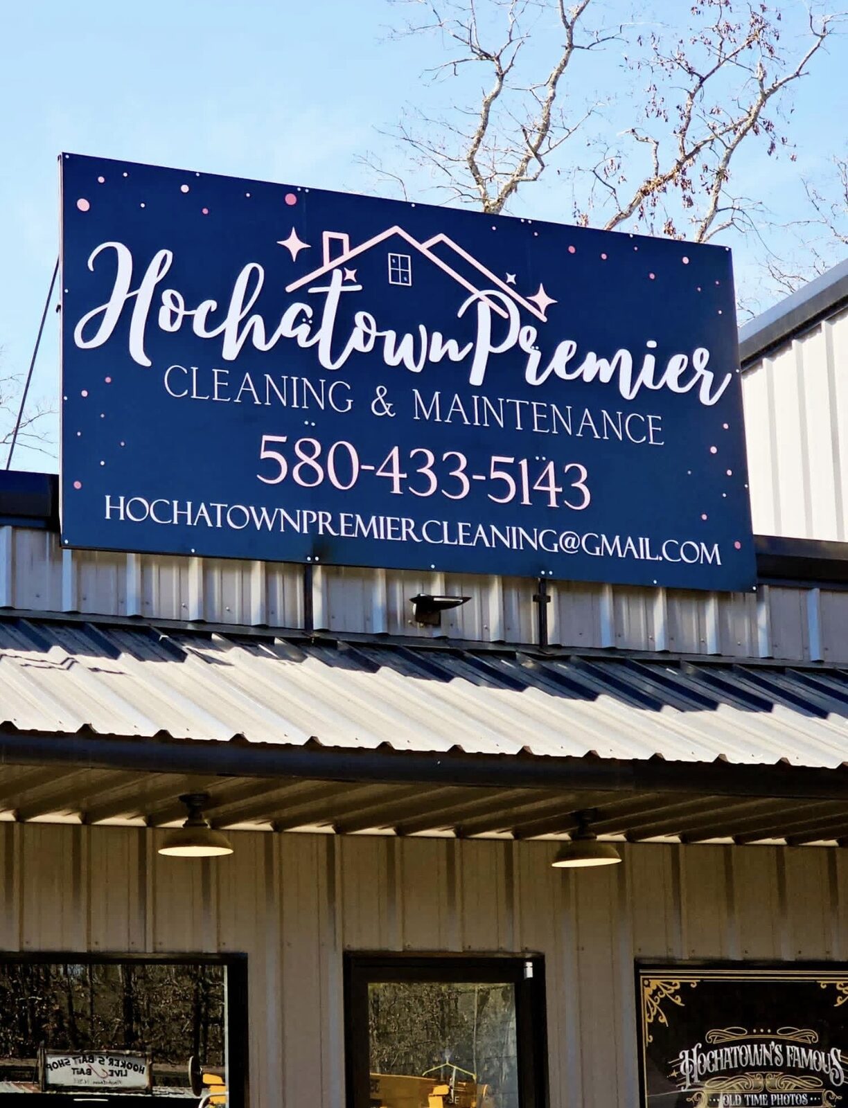 Hochatown Premier Cleaning & Maintenance sign — navy with a house logo, the phone number 580-433-5143 and the email — mounted above the storefront